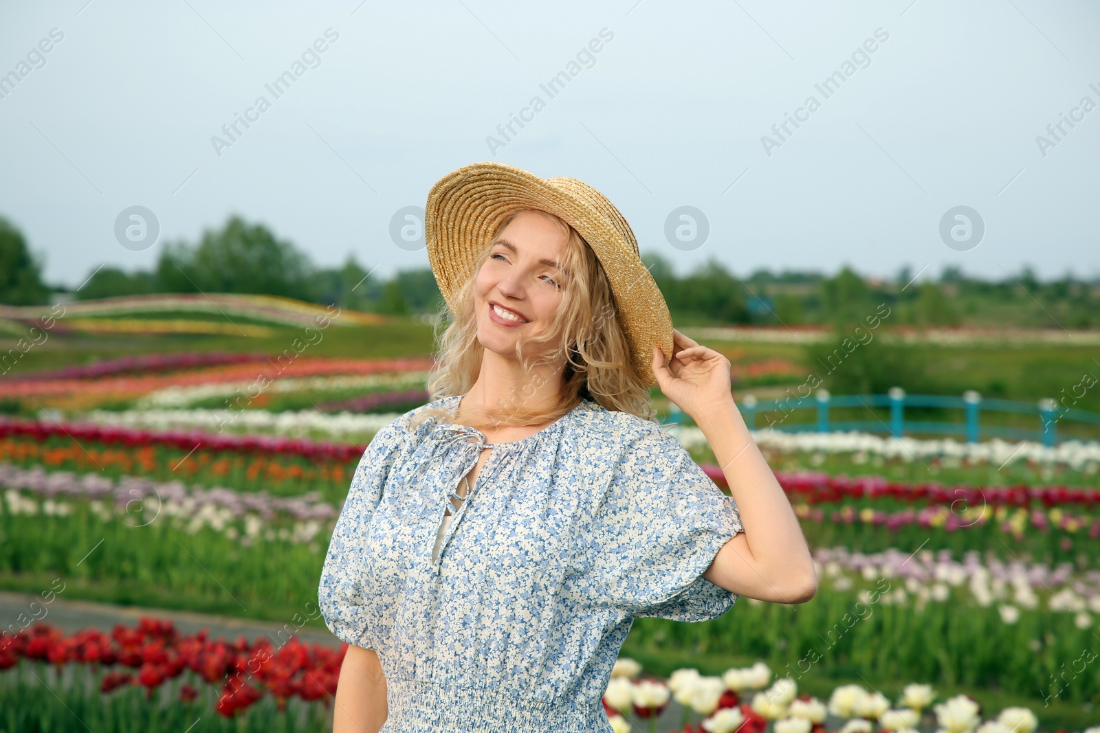 Photo of Happy woman in beautiful tulip field outdoors