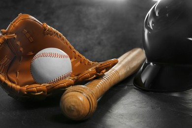 Photo of Baseball glove, bat, ball and batting helmet on black table, closeup