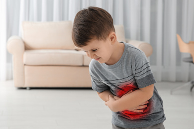 Image of Little boy suffering from stomach pain in living room