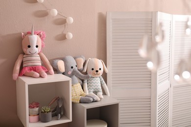 Photo of Soft toys on shelves near pink wall in child's room. Interior design