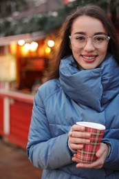 Photo of Woman with cup of mulled wine at winter fair