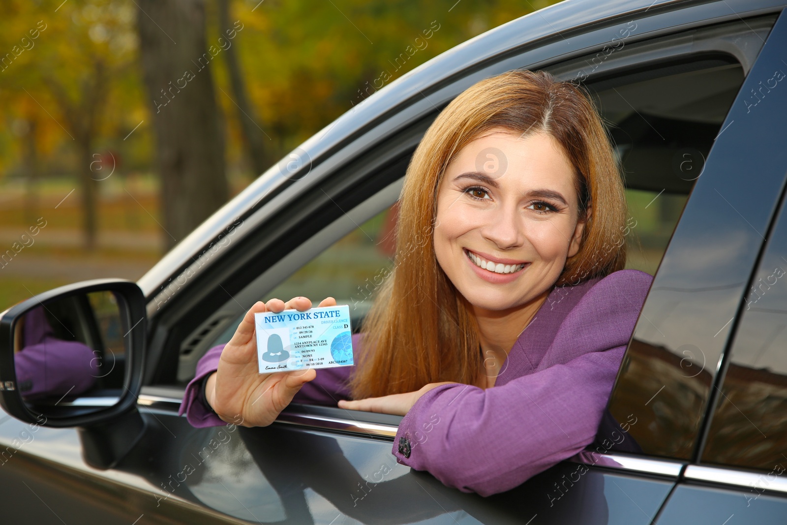 Photo of Happy woman holding driving license in car