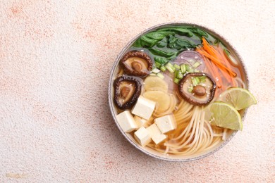 Photo of Bowl of vegetarian ramen on color textured table, top view. Space for text