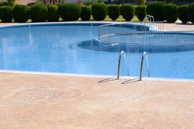 Clean swimming pool with metal ladder on sunny day outdoors