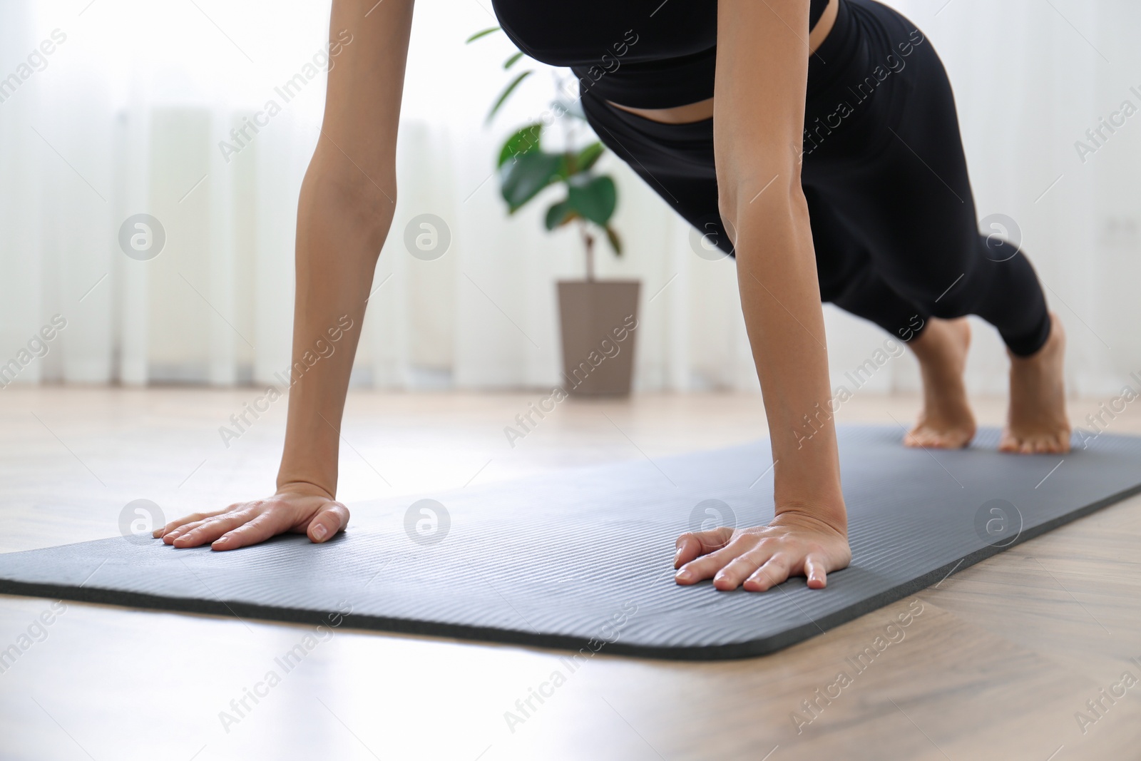 Photo of Young woman practicing plank asana in yoga studio, focus on hands. Phalakasana pose