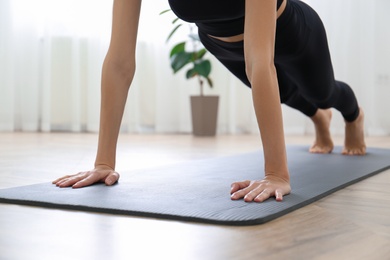 Photo of Young woman practicing plank asana in yoga studio, focus on hands. Phalakasana pose