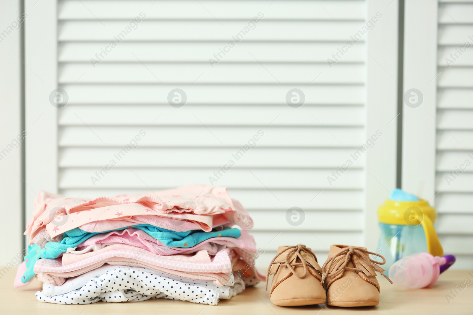 Photo of Pile of baby clothes and shoes on table