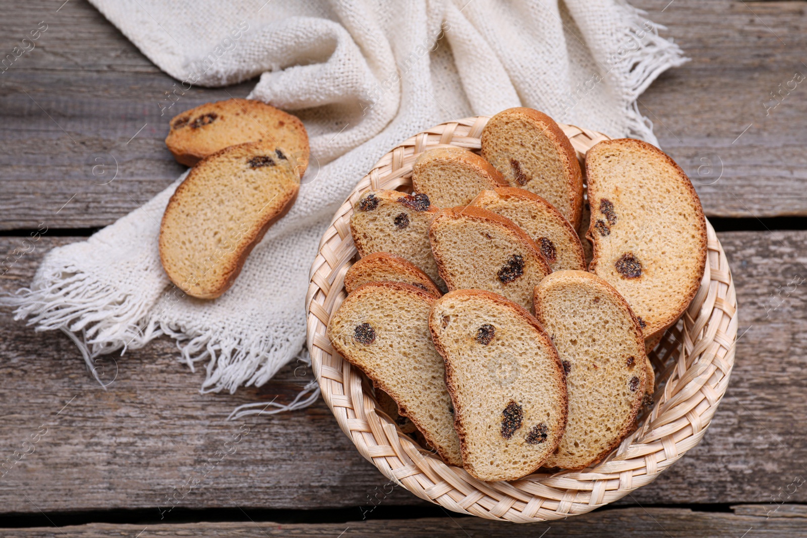 Photo of Sweet hard chuck crackers with raisins in wicker basket on wooden table, flat lay