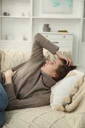 Photo of Sad young woman lying on sofa at home