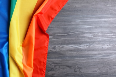 Photo of Bright rainbow gay flag on wooden background, top view with space for text. LGBT community