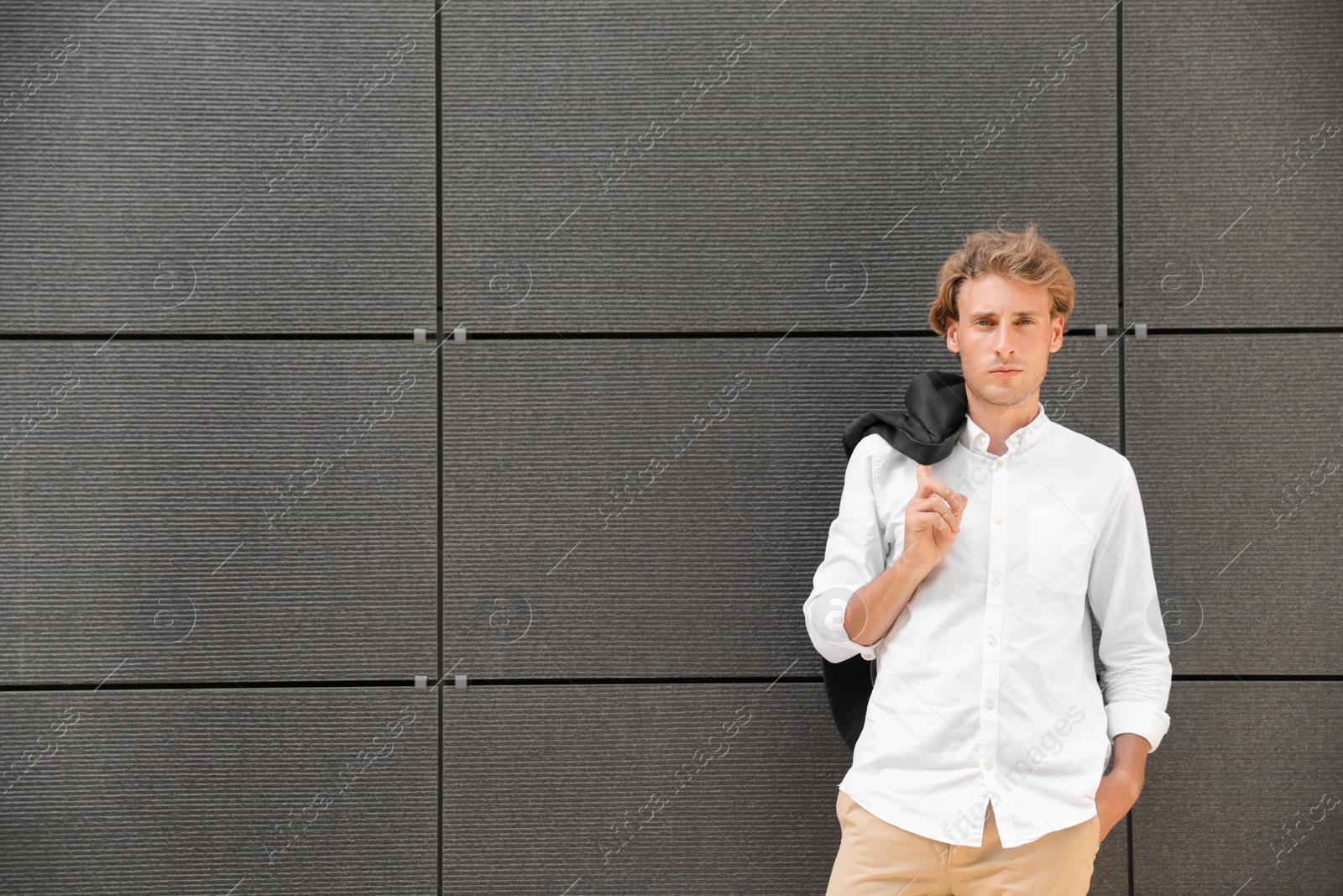 Photo of Portrait of handsome young man leaning to wall outdoors, space for text