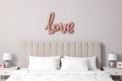 Photo of Cozy room interior with bed and balloon in shape of word Love. Valentine Day celebration