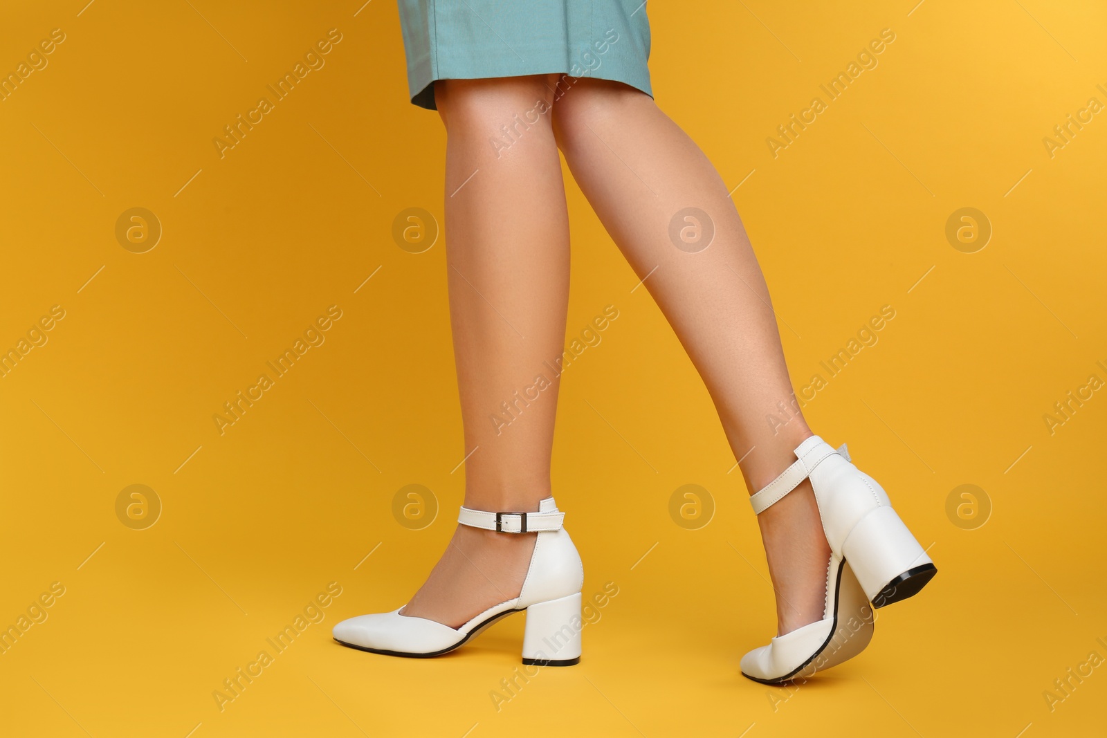 Photo of Woman wearing stylish shoes on yellow background, closeup
