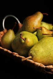 Tray with ripe pears on dark background, closeup