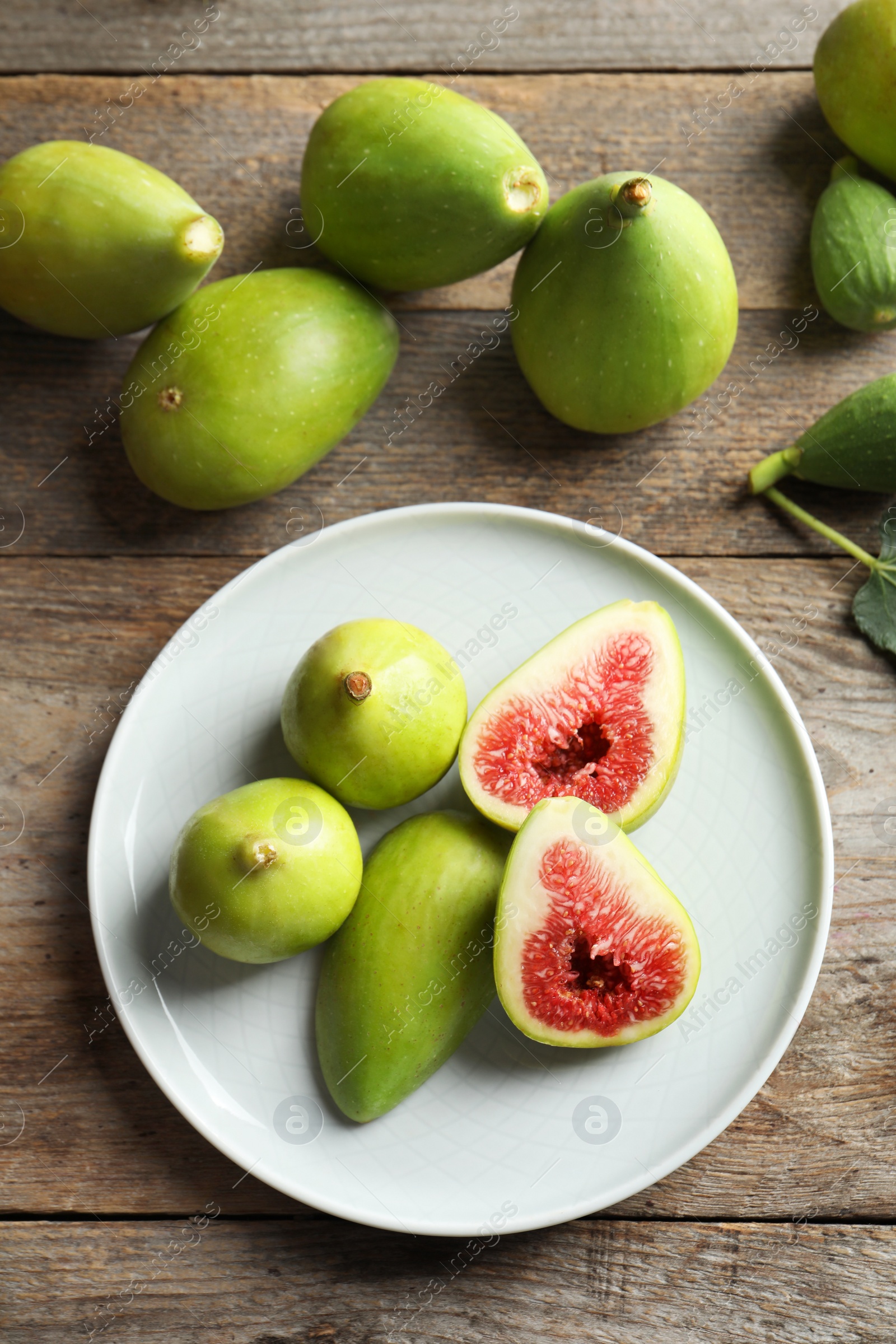 Photo of Plate with fresh ripe figs on wooden background, top view