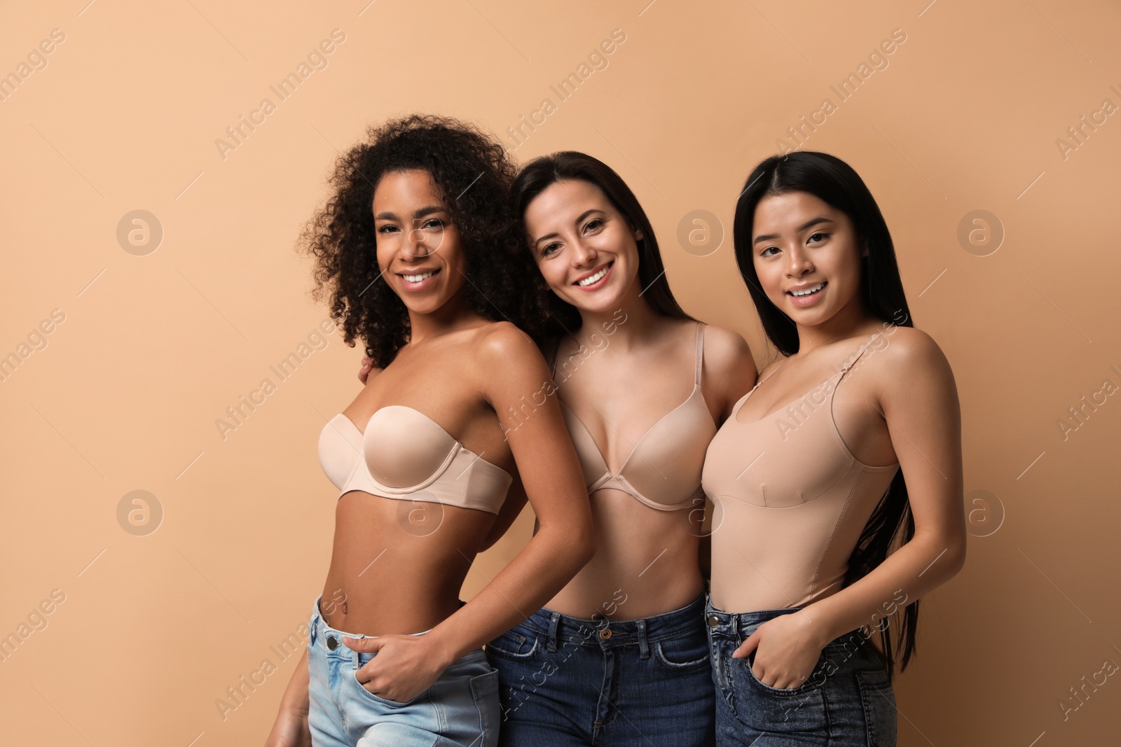 Photo of Group of women with different body types in jeans and underwear on beige background