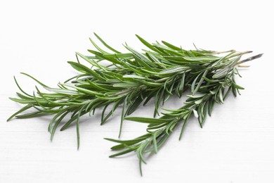 Photo of Fresh green rosemary twigs on white wooden table, closeup