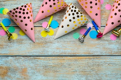 Photo of Colorful party hats and other festive items on wooden table, flat lay. Space for text