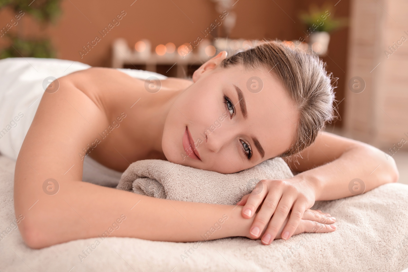 Photo of Young woman lying on massage table in spa salon