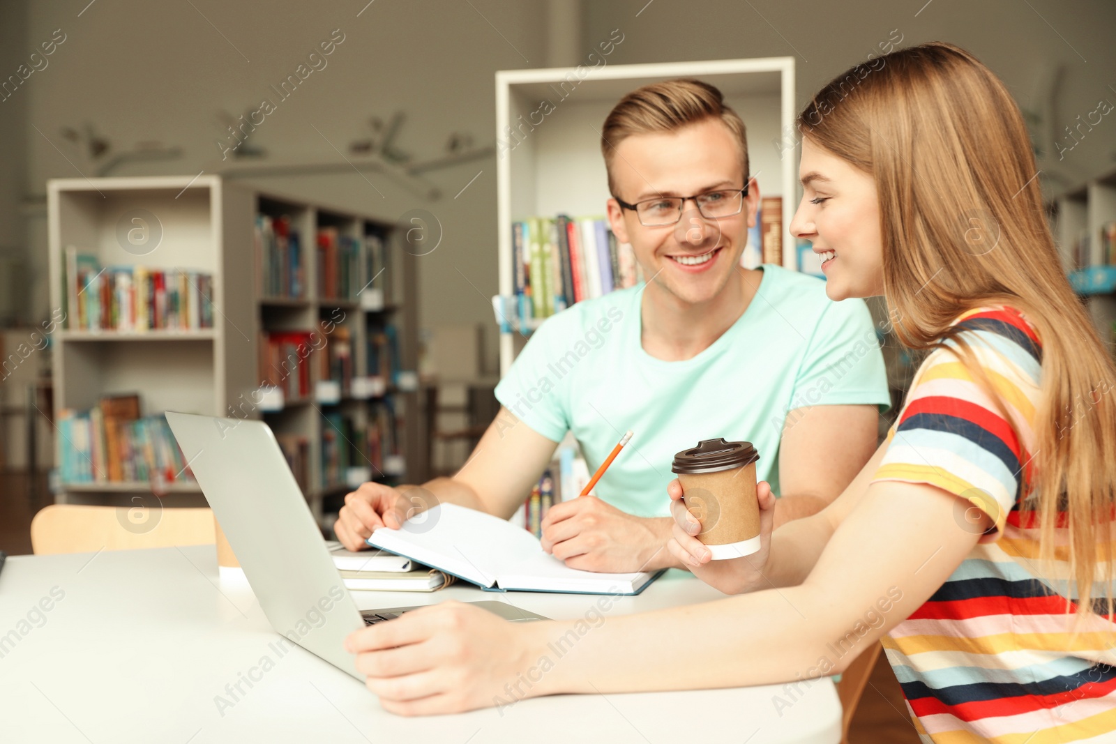 Photo of Young people discussing group project at table in library