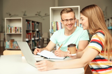 Young people discussing group project at table in library