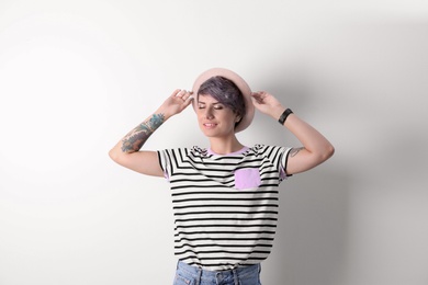 Trendy young woman with tattoos on white background