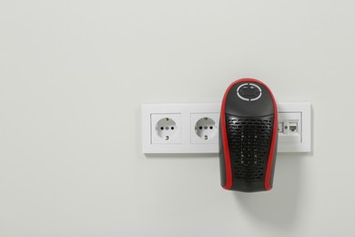 Photo of Compact electric heater charging from socket indoors, space for text