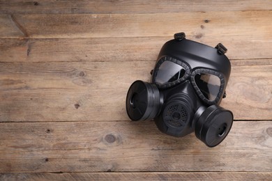 Photo of One gas mask on wooden background, top view. Space for text