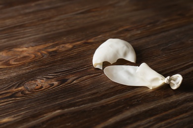 Photo of Popped balloon on wooden background, space for text