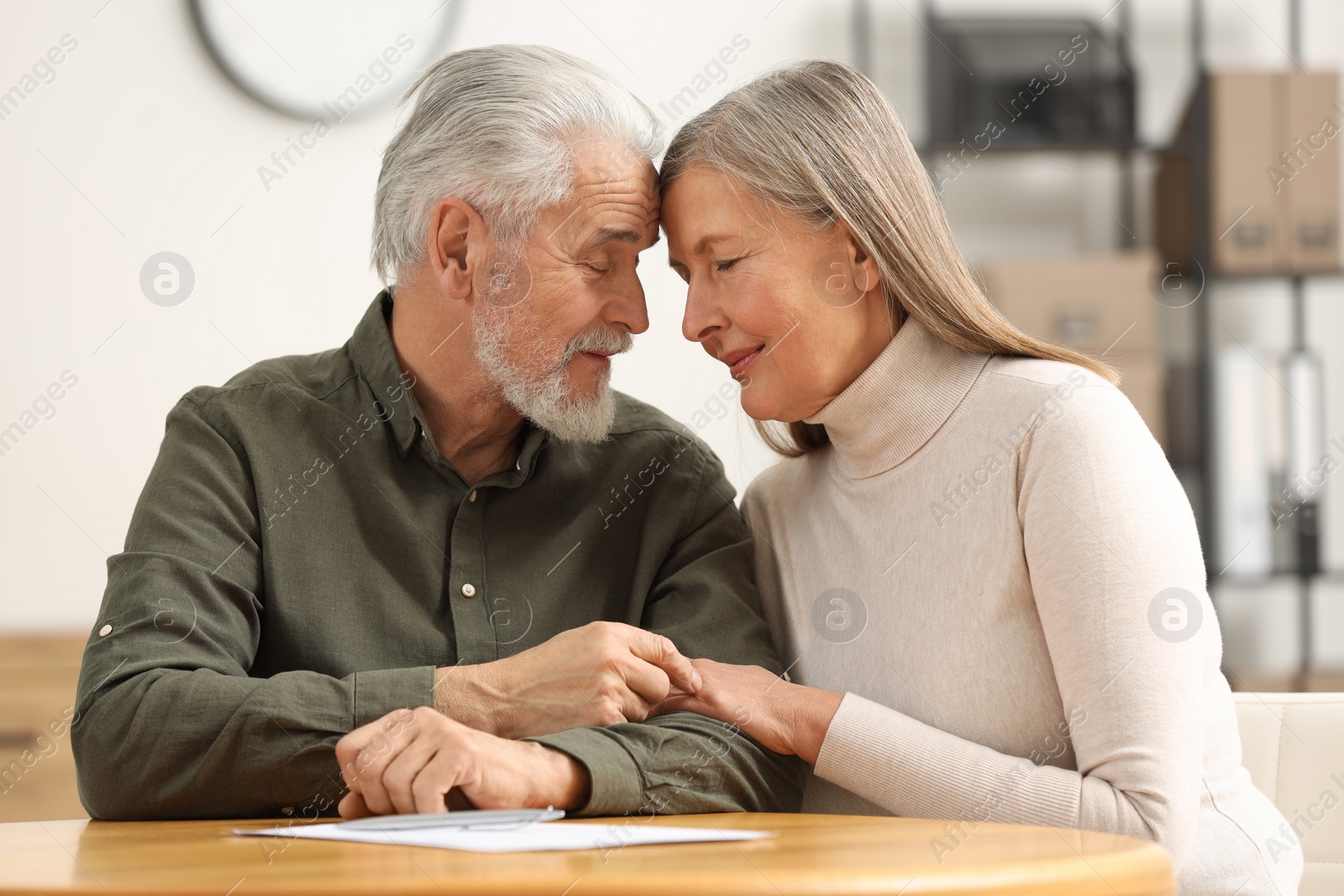 Photo of Senior couple signing Last Will and Testament indoors