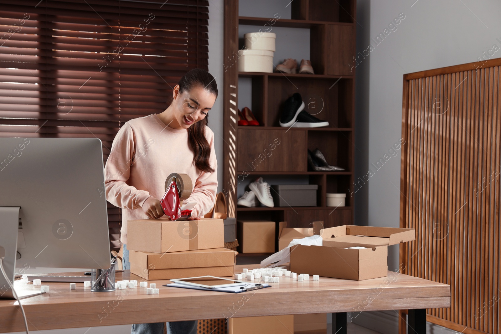 Photo of Seller taping parcel at workplace. Online store