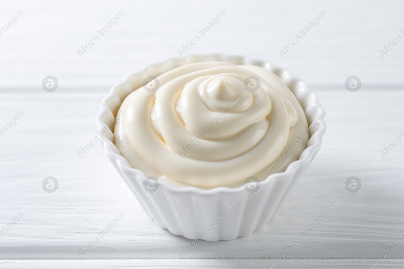 Photo of Fresh mayonnaise sauce in bowl on white wooden table, closeup