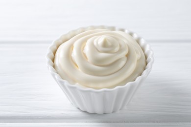 Photo of Fresh mayonnaise sauce in bowl on white wooden table, closeup