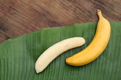 Photo of Delicious ripe bananas and fresh leaf on wooden table, flat lay. Space for text