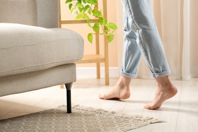 Photo of Woman stepping barefoot in room at home, closeup. Floor heating