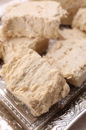 Photo of Pieces of tasty halva served on tray, closeup