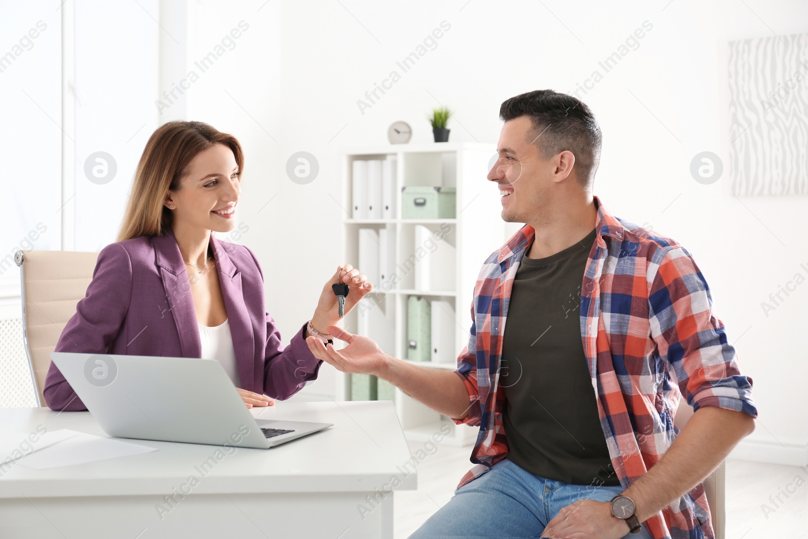 Photo of Real estate agent giving keys to client in office