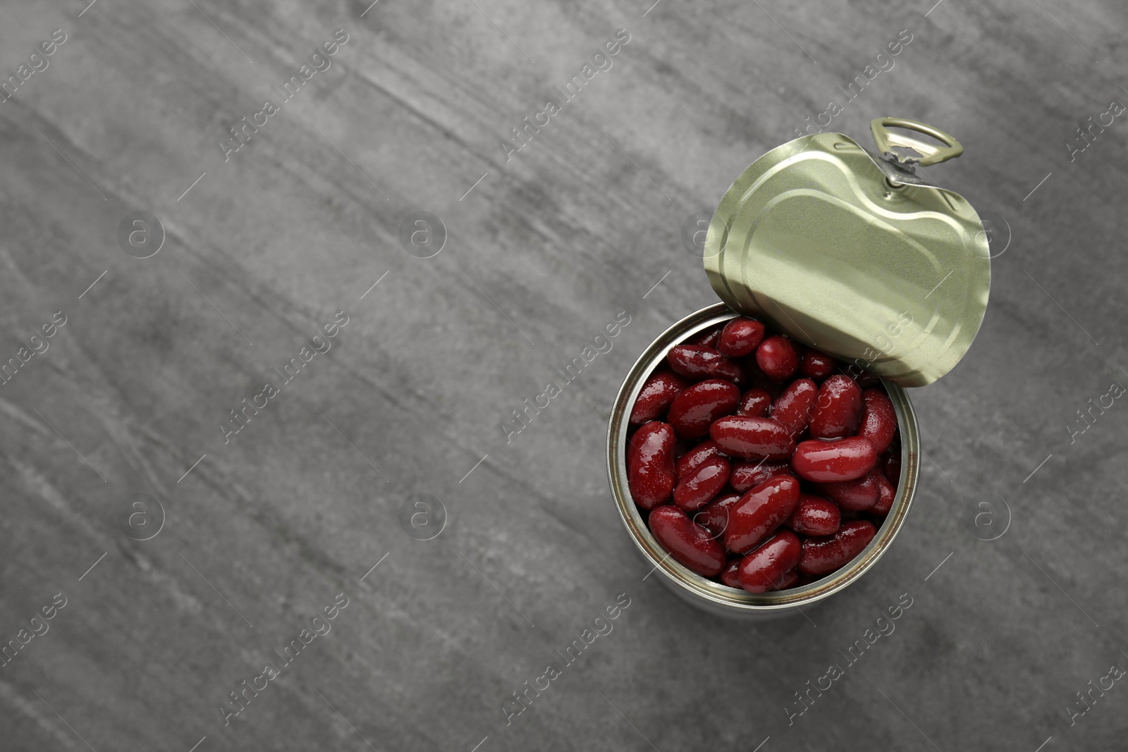 Photo of Tin can of canned red kidney beans on grey table, top view. Space for text