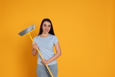 Photo of Beautiful young woman with broom on yellow background. Space for text
