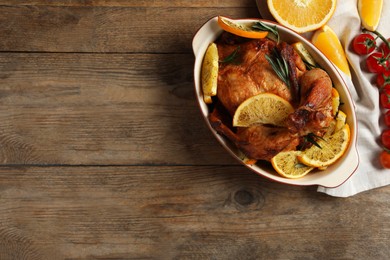 Photo of Baked chicken with orange slices on wooden table, flat lay. Space for text