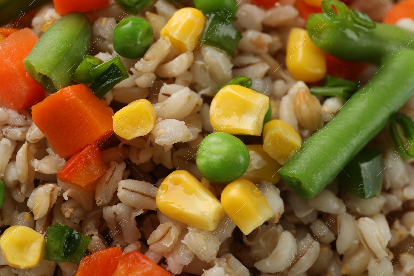 Photo of Tasty pearl barley porridge with vegetables as background, closeup