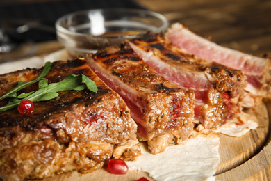 Photo of Delicious grilled ribs on wooden board, closeup