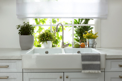 Photo of Beautiful white sink near window in modern kitchen