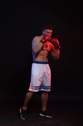 Photo of Man wearing boxing gloves on black background