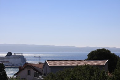 Photo of Beautiful view of buildings and calm sea with cruise under blue sky