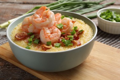 Fresh tasty shrimps, bacon, grits and green onion in bowl on wooden table, closeup