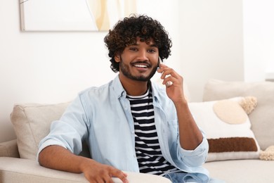 Photo of Handsome smiling man taking on smartphone in room