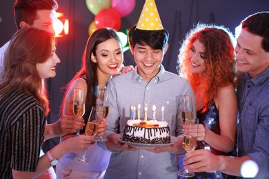 Photo of Young people celebrating birthday with cake in nightclub