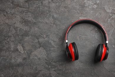 Stylish modern headphones and space for text on concrete background, top view