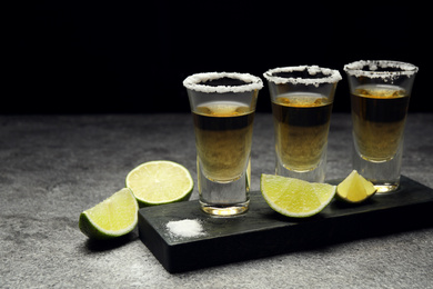 Photo of Mexican Tequila shots, lime slices and salt on grey table